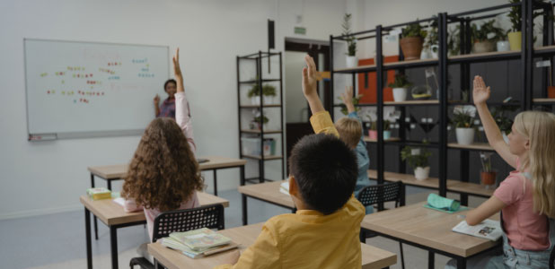 Kids in a classroom raising their hands